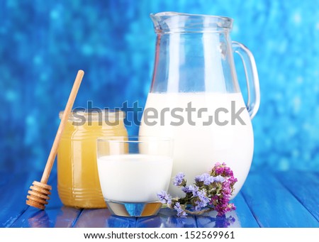 Honey and milk on wooden table on blue background