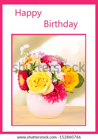 Beautiful bouquet of bright flowers in color vase, on wooden table, on bright background