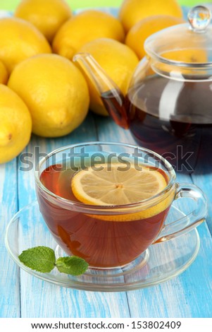 Cup of tea with lemon on table on blue background