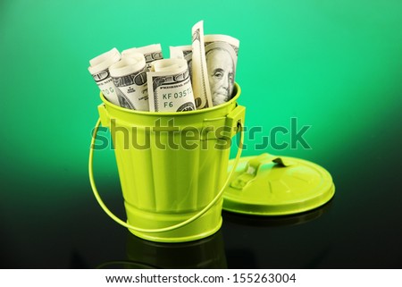 Money in  trash can, on dark background