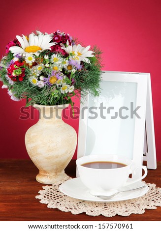 Beautiful bright flowers in vase on table on pink background