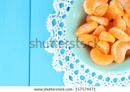 Tasty mandarine\'s slices on color plate on blue background