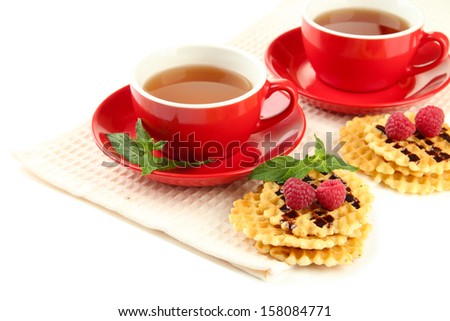 Cups of tea with cookies and raspberries isolated on white