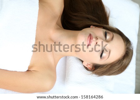 Beautiful young woman on massage table in cosmetic salon close up