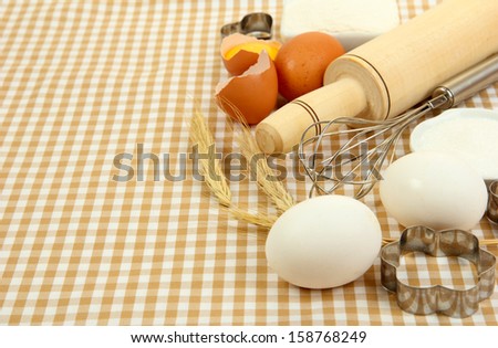 Cooking concept. Basic baking ingredients and kitchen tools on tablecloth background