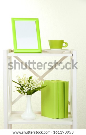 Composition of various home furnishing on white shelf on grey wall background