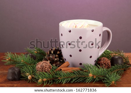 Cup of hot cacao with chocolates and fir branches on table on dark background
