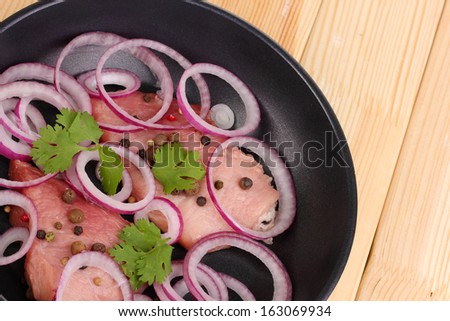 A pieces of pork with onions fried in pan close-up on wooden table