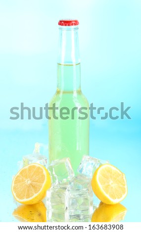 Drink in glass bottle with ice cubes on blue background