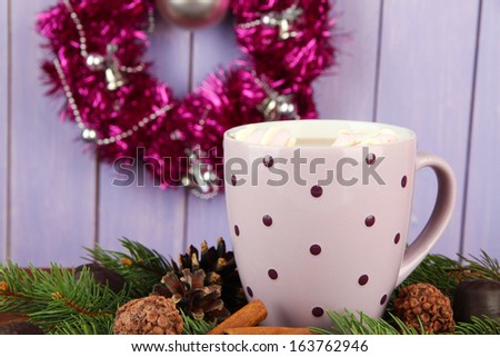 Cup of hot cacao with chocolates and fir branches on table on wooden background