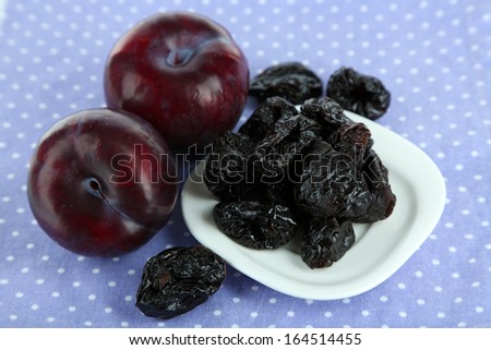 Fresh and dried plums, on color background