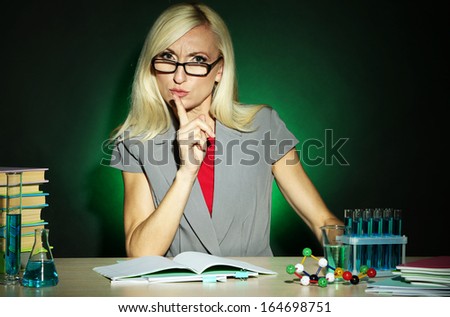 Wicked chemistry teacher sitting at table on dark colorful background