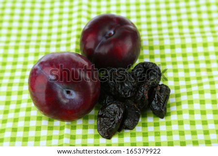 Fresh and dried plums, on color background