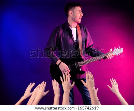 Guitarist singing on stage at a rock concert for his adoring fans