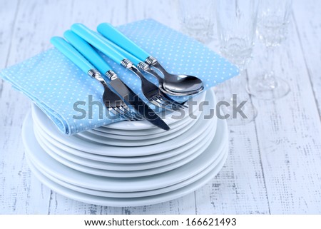 Clean dishes on wooden table on light background
