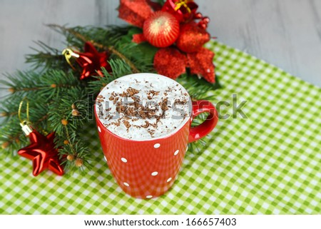 Hot chocolate with cream in color mug, on napkin, on Christmas decorations background
