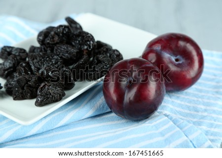 Fresh and dried plums  on napkin, on wooden background