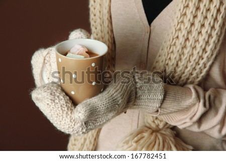 Female hands with hot drink, on color background
