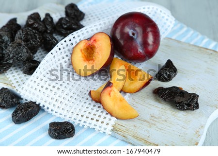 Fresh and dried plums  on napkin, on wooden background