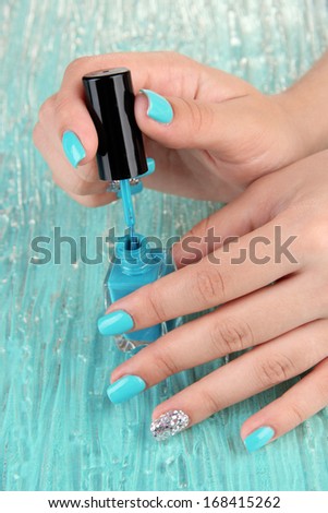 Beautiful woman hands with blue manicure, on color background