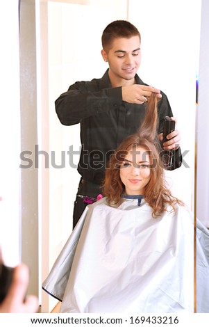 Young man hairdresser do hairstyle girl in beauty salon