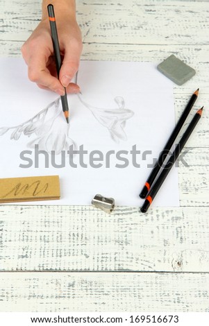 Hand draws a sketch with professional art materials, on wooden table