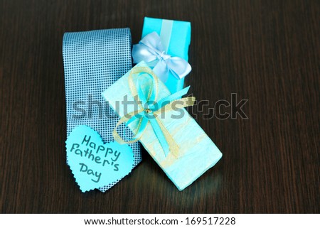 Happy Fathers Day tag with gift boxes and tie, on wooden background