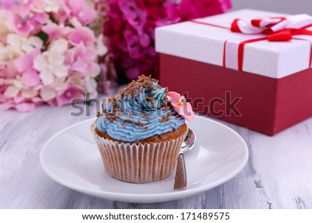 Tasty cupcake with butter cream, on plate, on color wooden background
