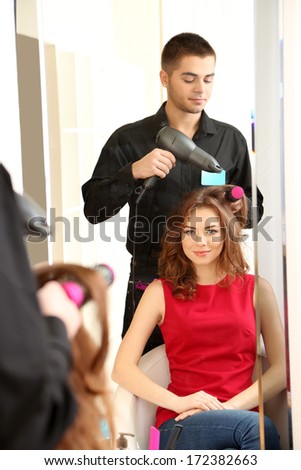 Young man hairdresser do hairstyle girl in beauty salon
