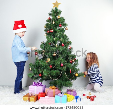 Kids decorating Christmas tree with baubles in room