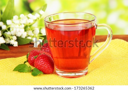 Delicious strawberry tea on table on bright background