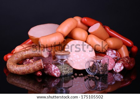 Lot of different sausages with spices on black background
