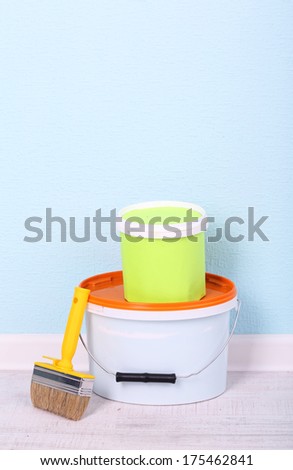 Paints and paintbrush on floor in room on wall background