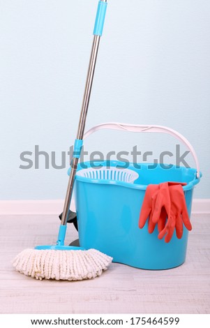 Floor mop and bucket for washing in room on blue wall background