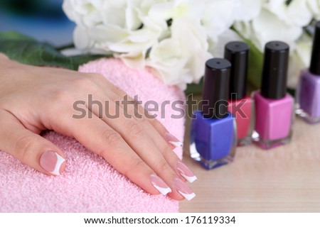 Beautiful woman hands with french manicure and flower on table close up