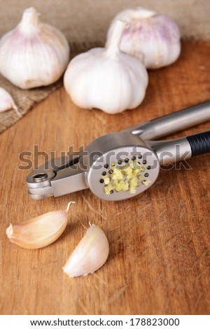 Garlic press with garlic on wooden background