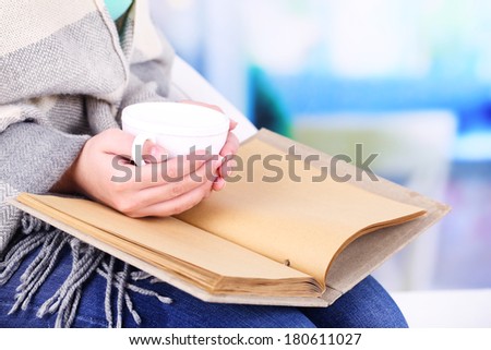 Woman reading book and  drink coffee or tea, close-up