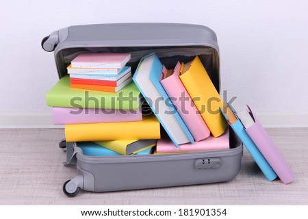Books in suitcase on wall background