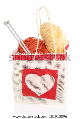 Woolen balls of yarn and wooden knitting needles in rustic craft bag, isolated on white