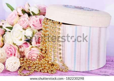 Decorative box with beads and flowers on table on bright background