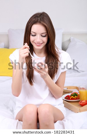 Young beautiful woman on bed with light breakfast