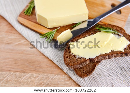 Slice of rye bread with butter on wooden cutting board
