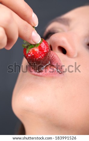Closeup of woman eating strawberry in chocolate