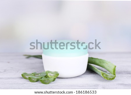 Cream and fresh green aloe leaves on wooden table