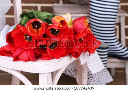 Bouquet of colorful tulips on chair, on home interior background