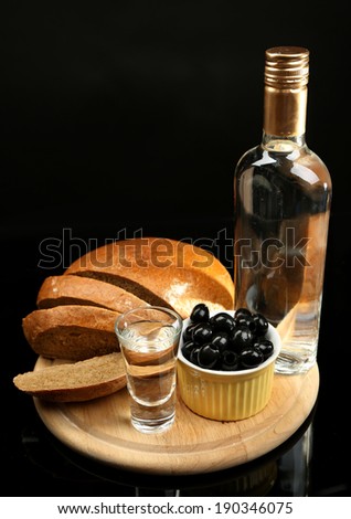 Composition with bottle of vodka, glasses, and marinated olives on wooden board, isolated on black