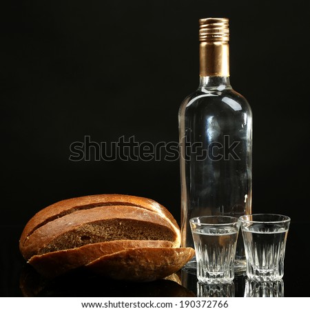 Bottle of vodka, fresh bread and glasses isolated on black