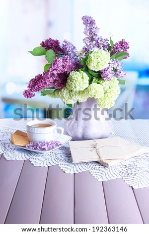 Composition with  cup of tea, old letters and beautiful spring flowers in vase, on wooden table, on bright background