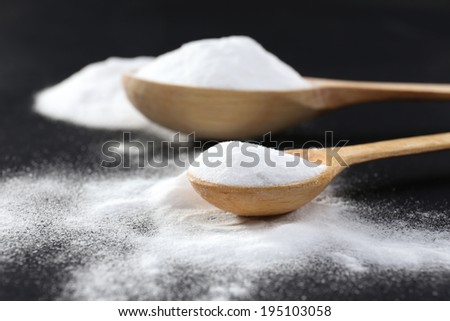 Spoons of baking soda on black background