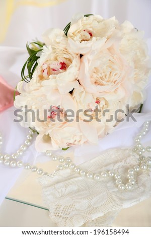 Beautiful wedding bouquet and decorative pillow for wedding rings on chair on light background